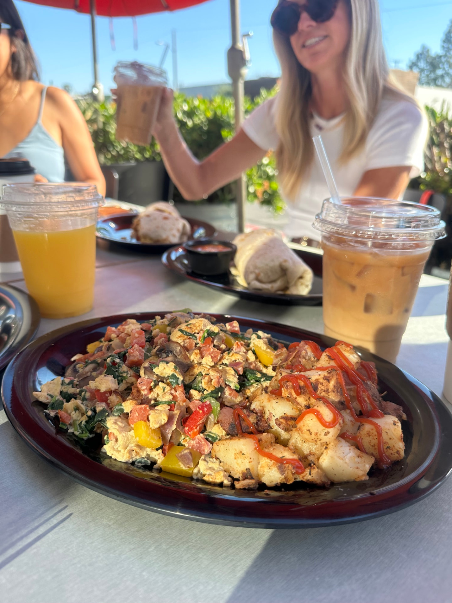 A veggie-packed plate with breakfast potatoes and iced coffee on the Rooster Cafe patio